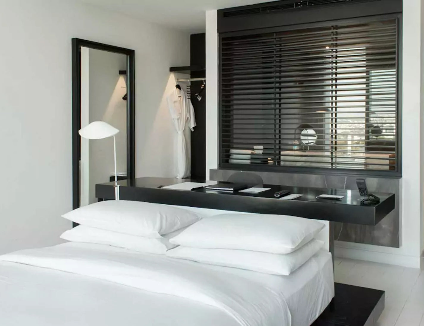 White Serge Mouille Agrafee Desk Lamp clamped to a bed head board