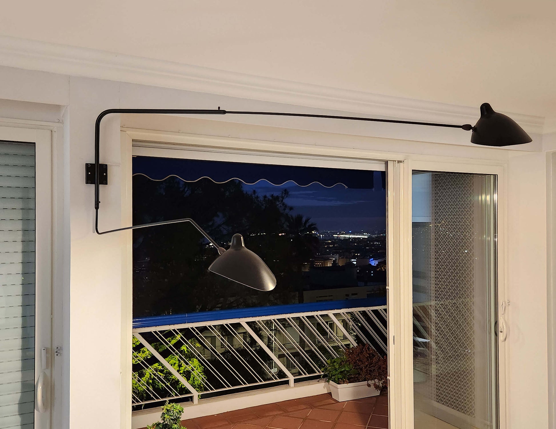 Black Serge Mouille Rotating Sconce 2 Arms 1 Curved Arm shown in an apartment