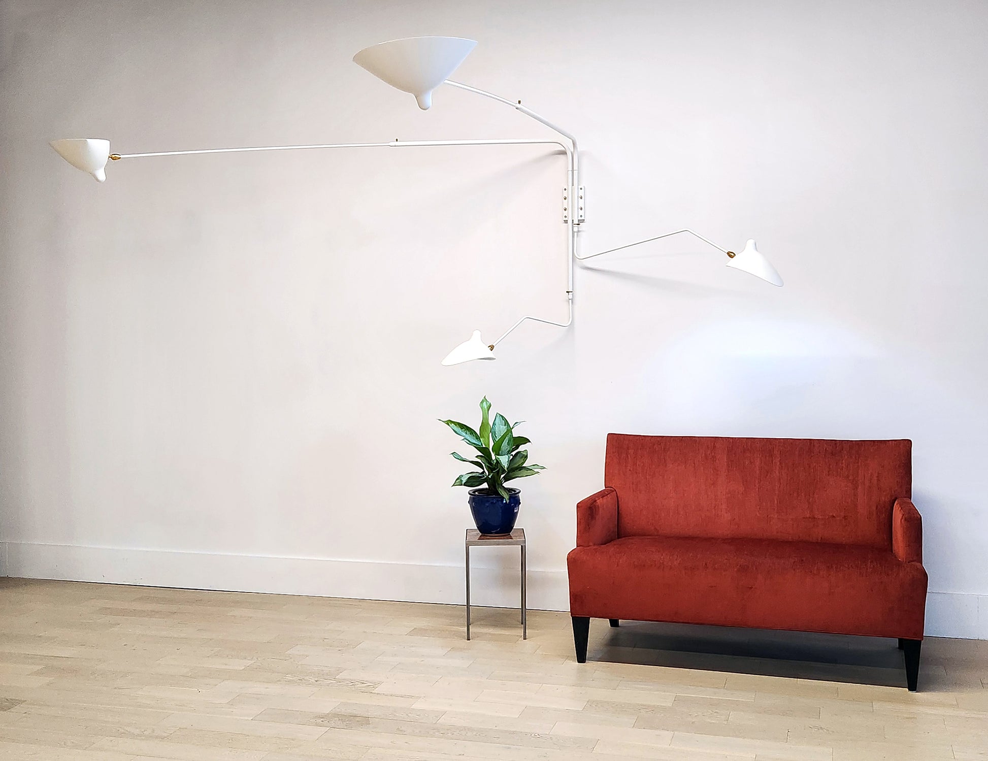 White Serge Mouille Rotating Sconce with 4 Arms with red sofa and plant (3)