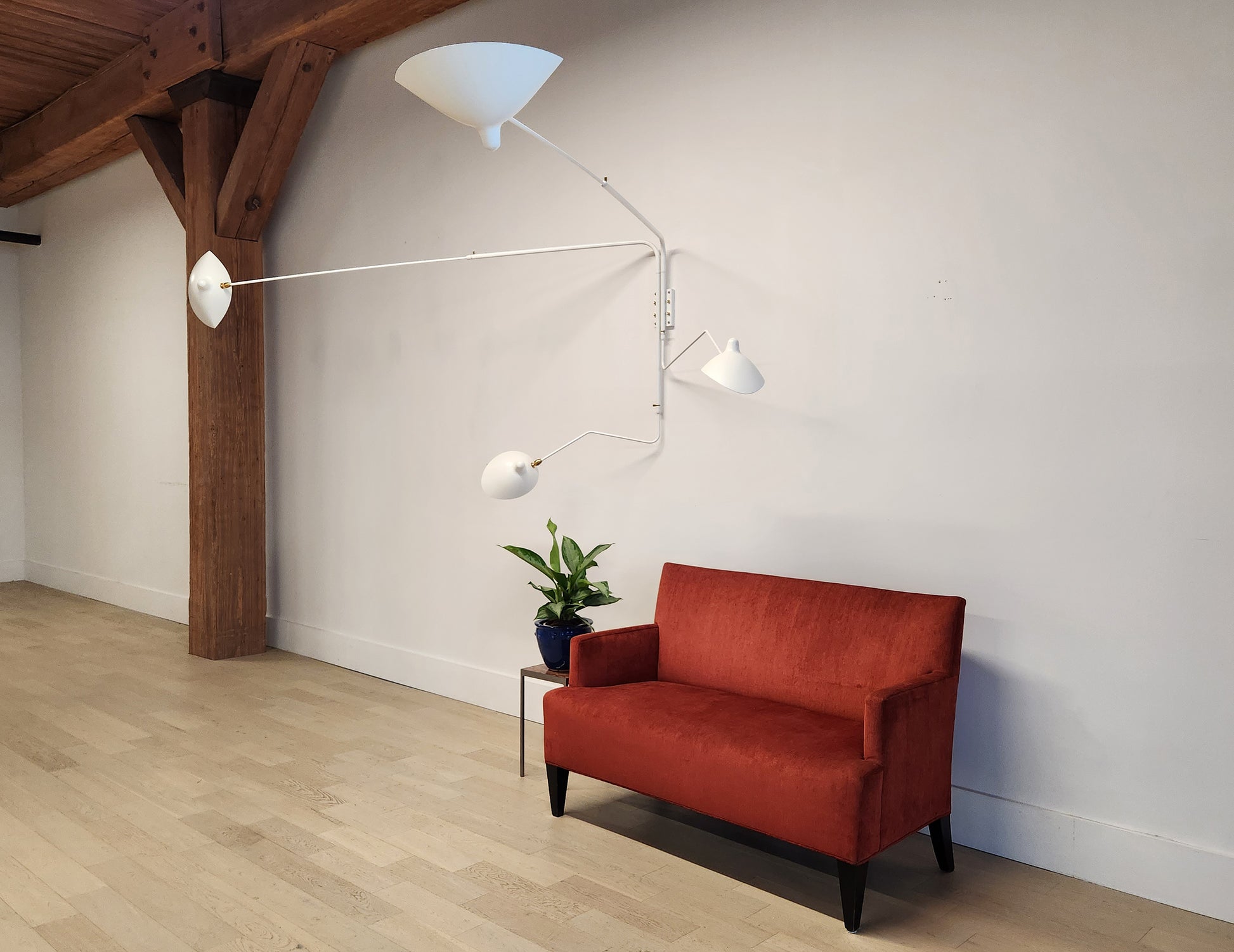 White Serge Mouille Rotating Sconce with 4 Arms with red sofa and plant (4)