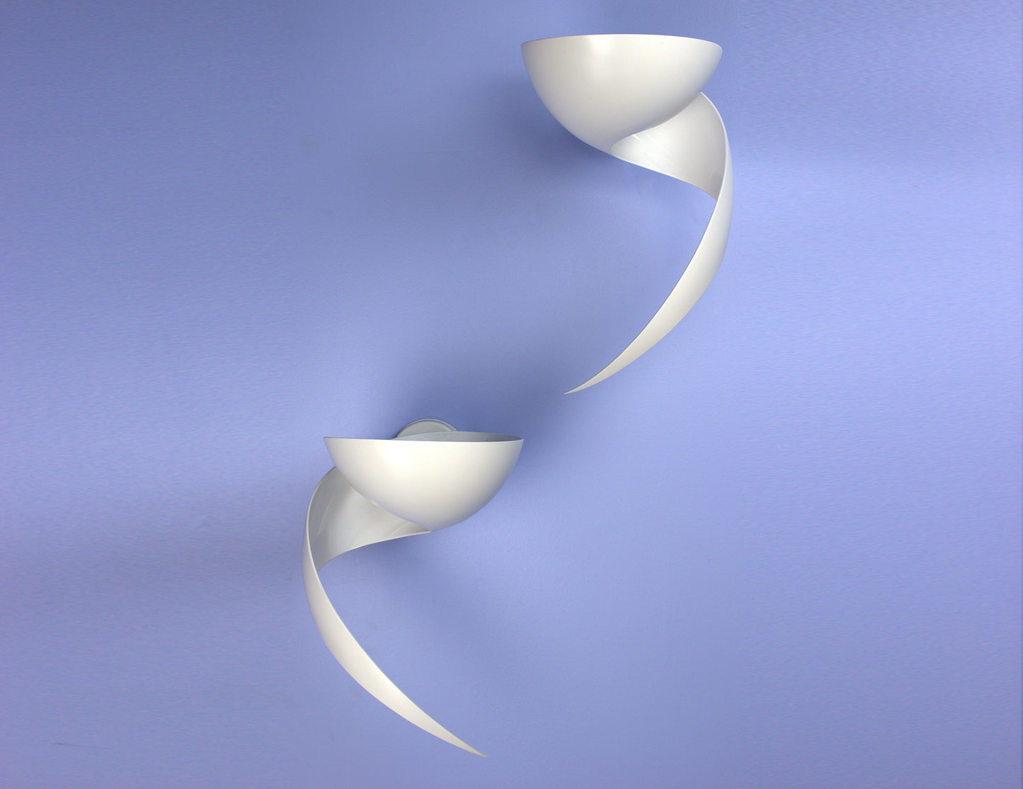 Pair of white Serge Mouille Flame Sconces on blue wall