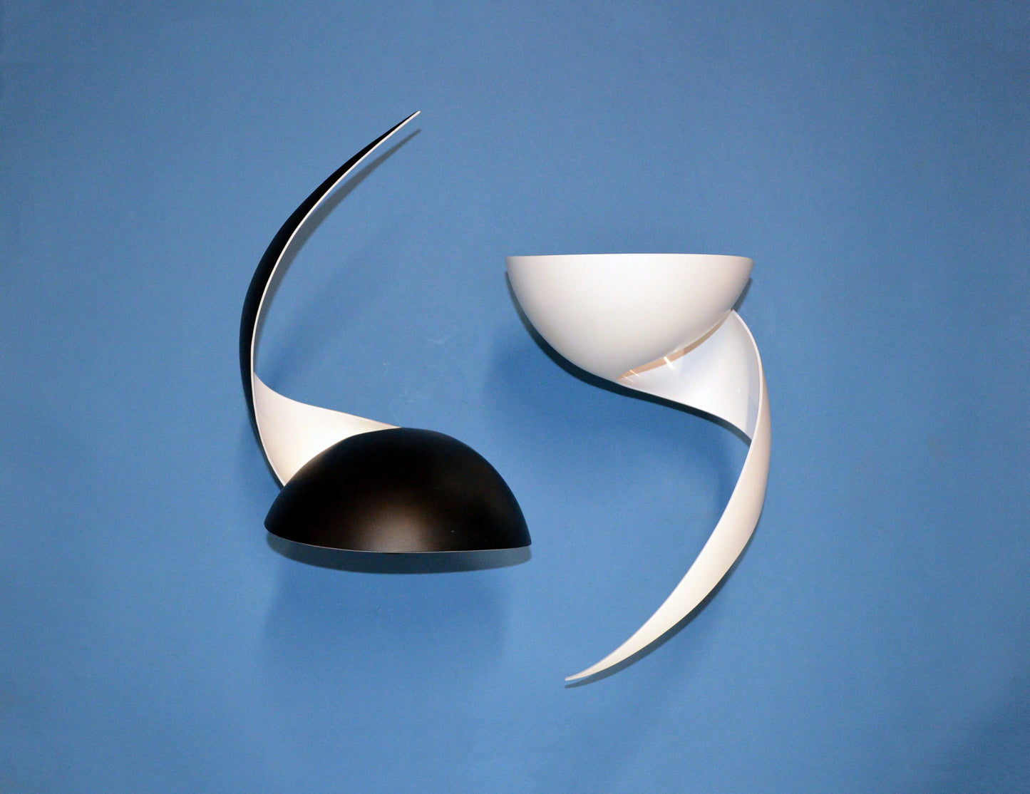 Pair of Serge Mouille Flame Sconces (1 black and 1 white) on blue wall