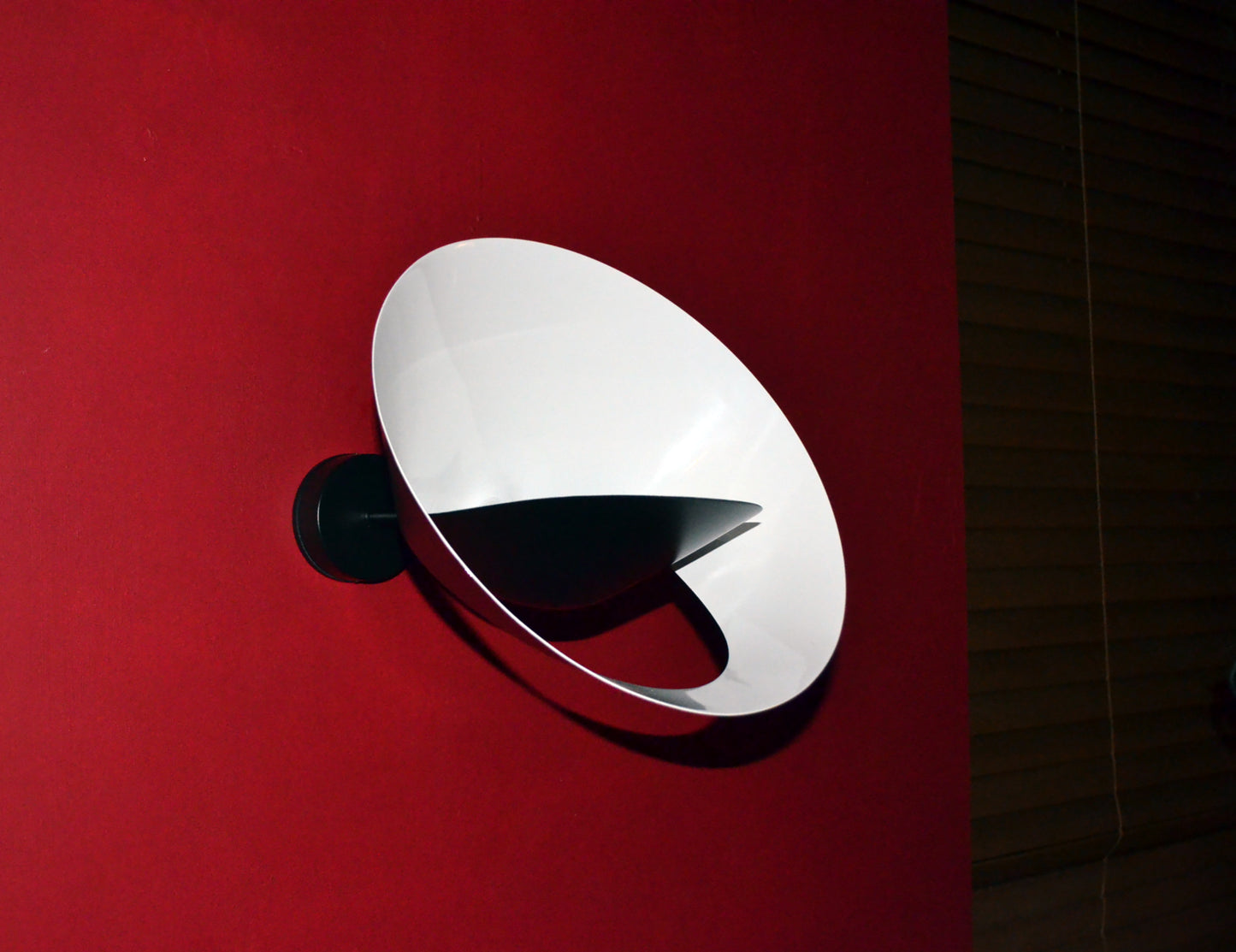 Black Serge Mouille Saturn Sconce on a red wall