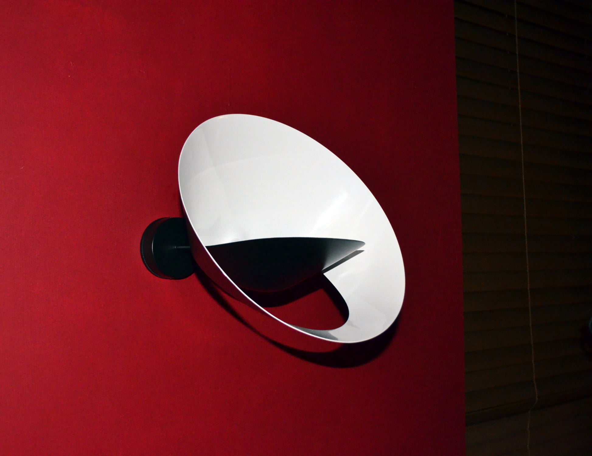 Black Serge Mouille Saturn Sconce on a red wall