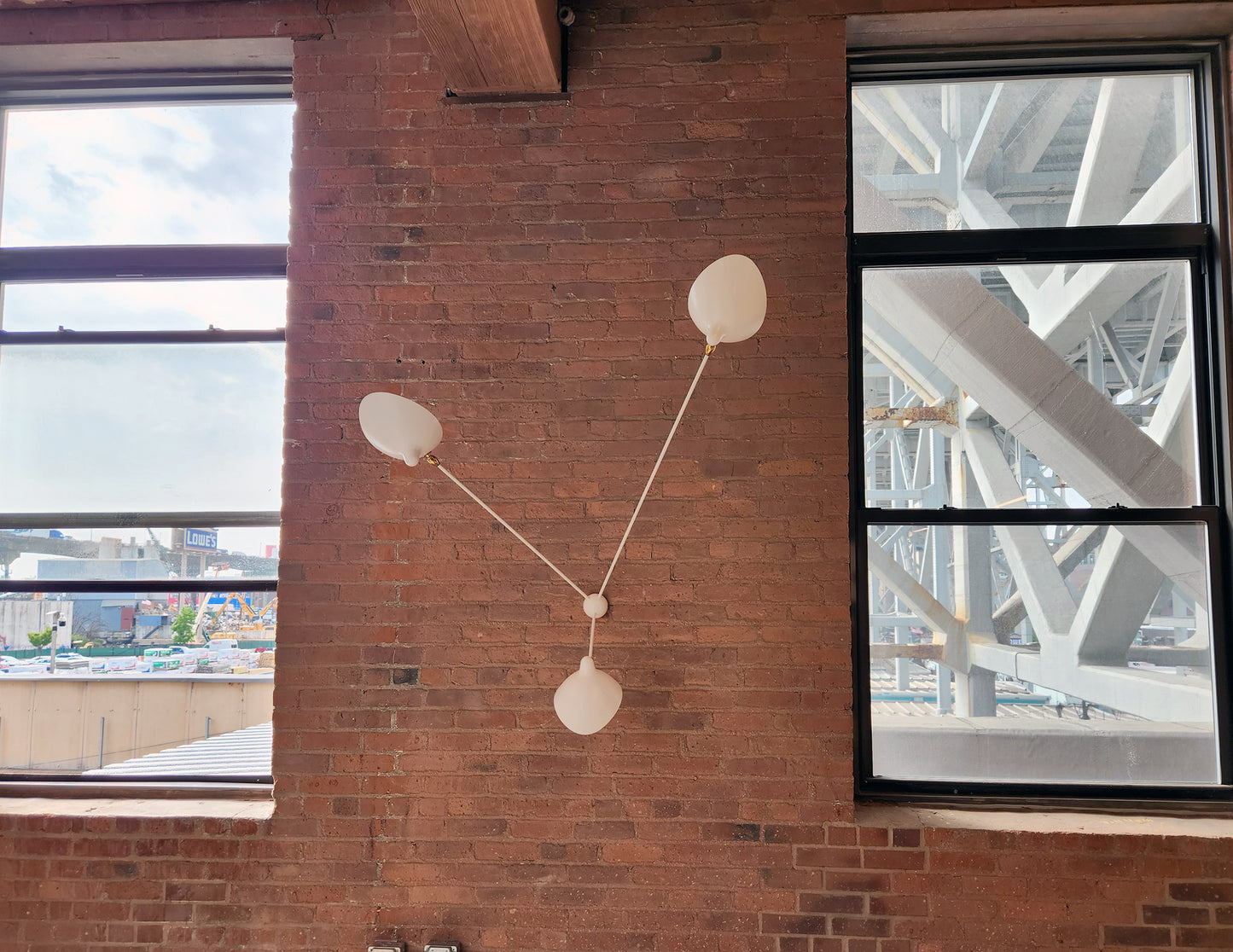 White Serge Mouille Spider Sconce with 3 Arms on a brick wall