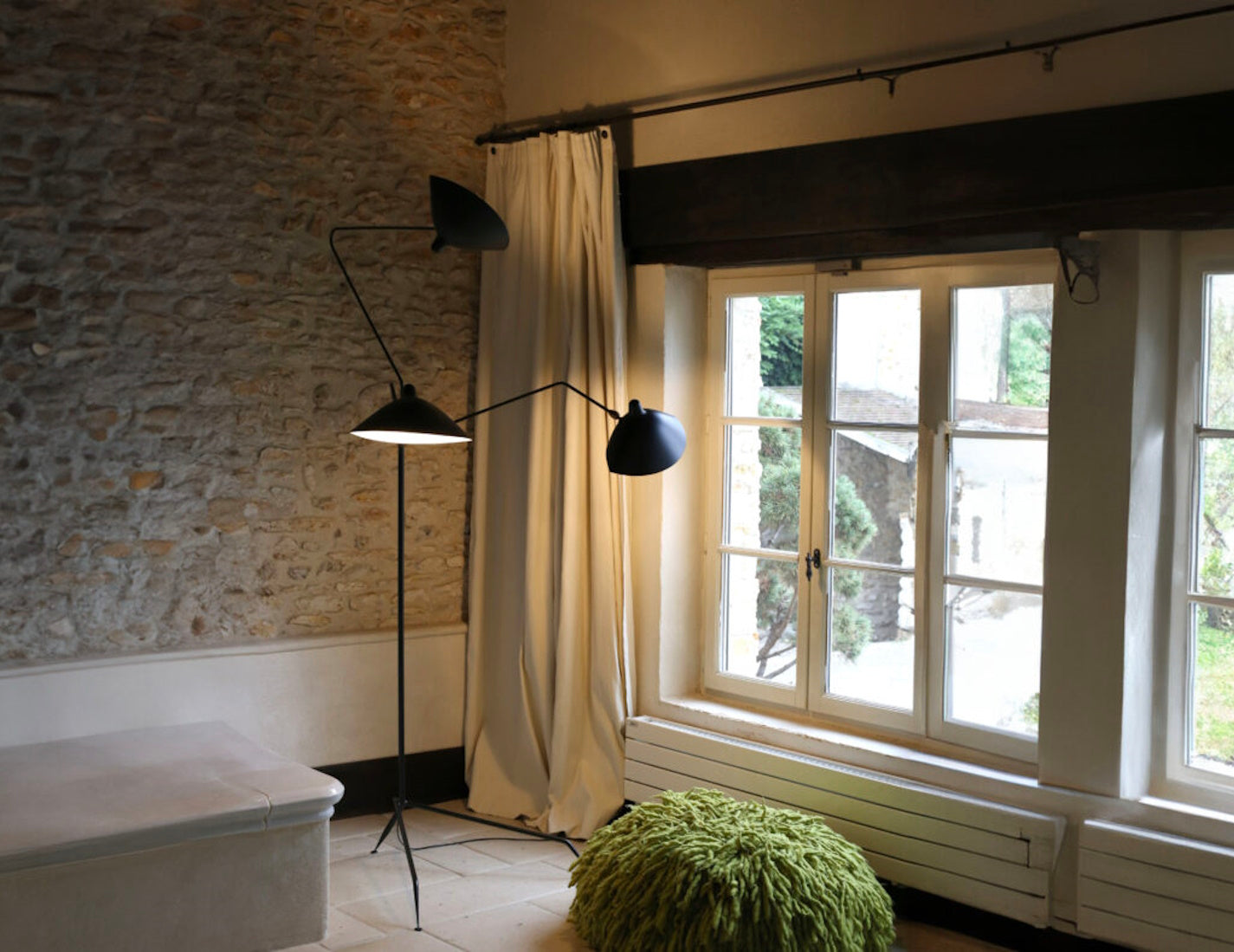 Black Serge Mouille Floor Lamp with 3 Arms shown in the corner of a room
