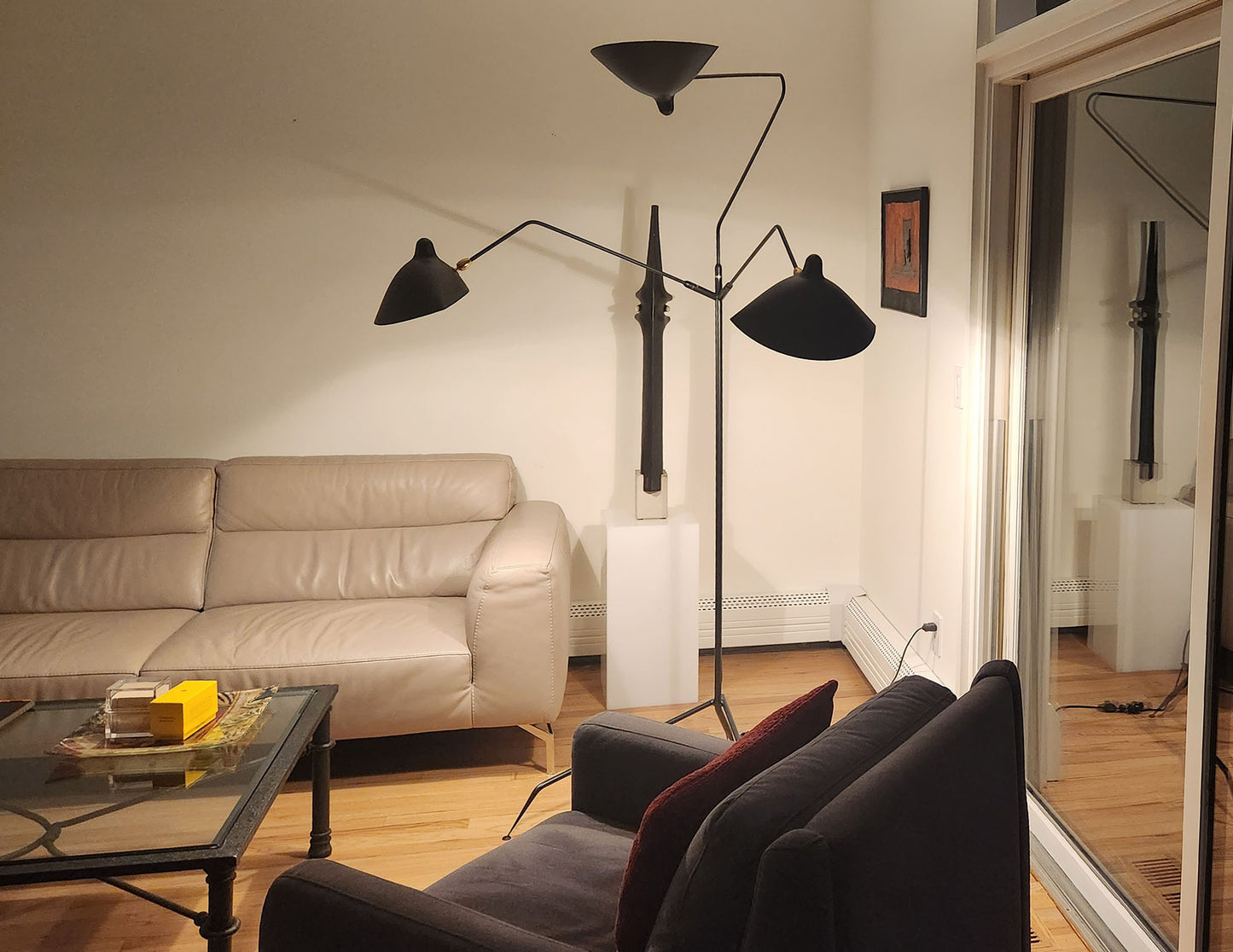 Black Serge Mouille Floor Lamp with 3 Arms shown in the corner of a living room