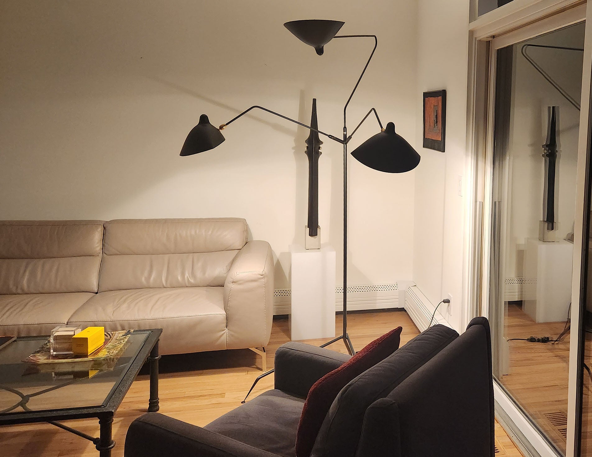 Black Serge Mouille Floor Lamp with 3 Arms shown in the corner of a living room