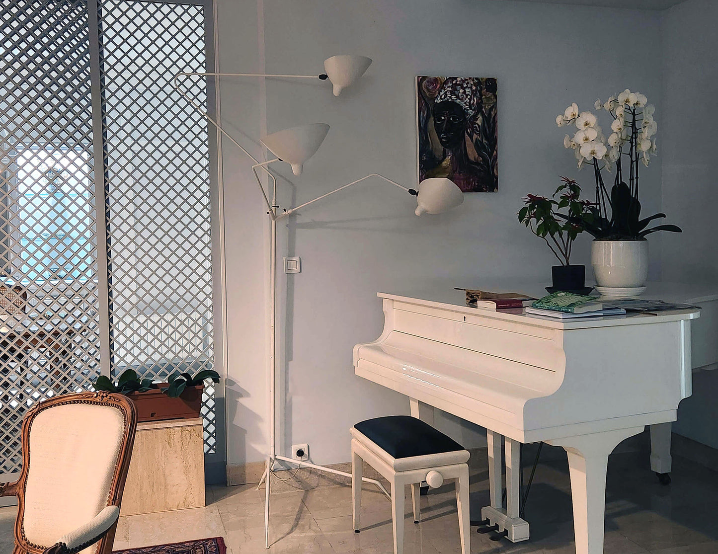 White Serge Mouille Floor Lamp with 3 Arms shown next to a white piano