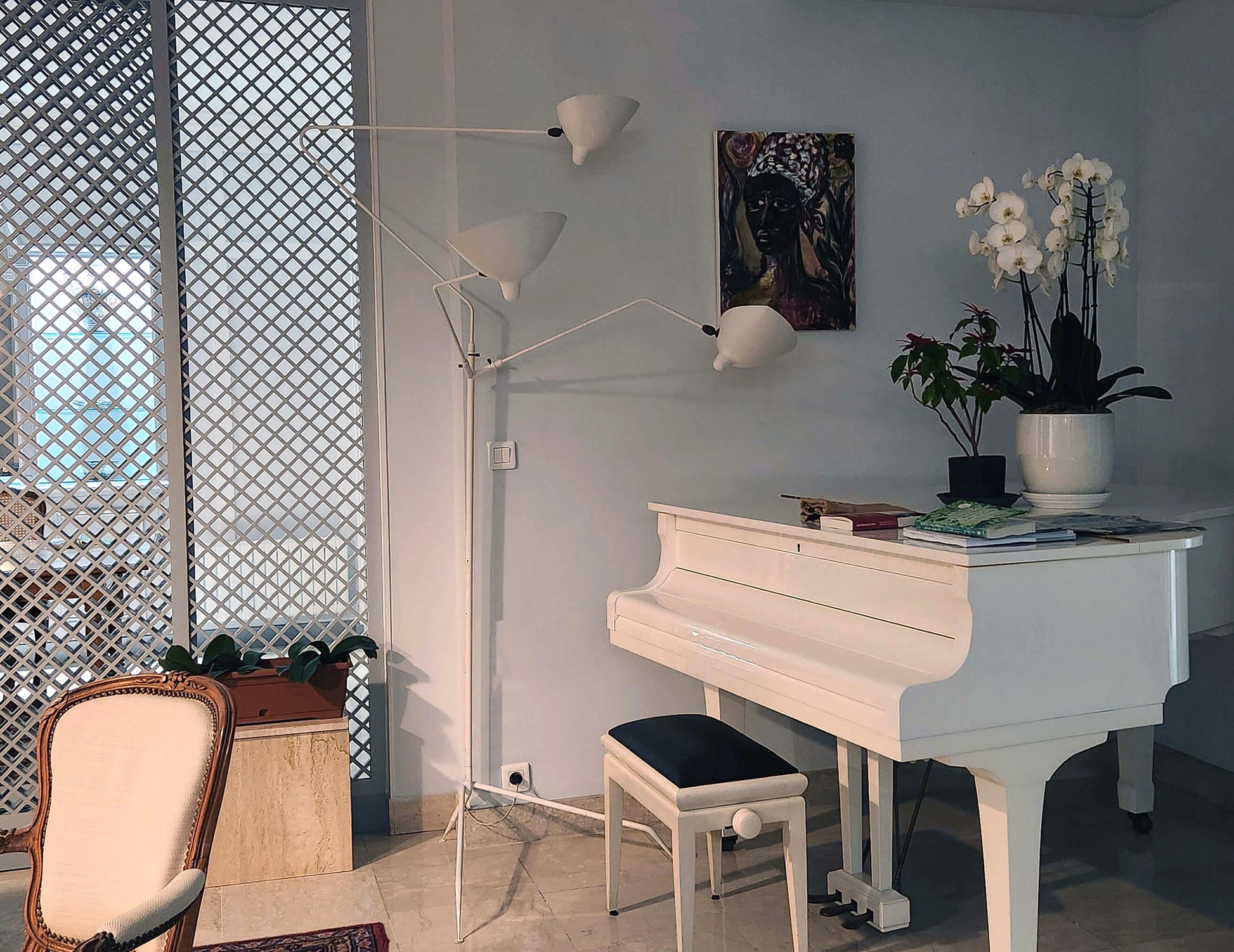 White Serge Mouille Floor Lamp with 3 Arms shown next to a white piano