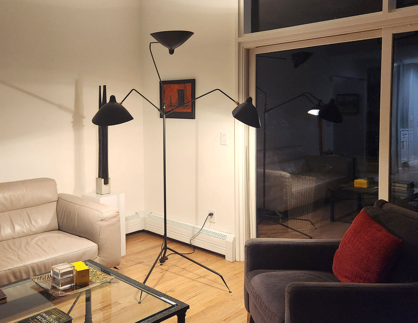 Black Serge Mouille Floor Lamp with 3 Arms shown in the corner of a living room